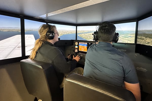 Two persons in the cockpit of a large flight simulator.