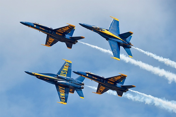 Four US Navy Blue Angels fly in formation through a clear blue sky