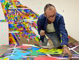 Ralph Ziman hunched over work table with colorful panels